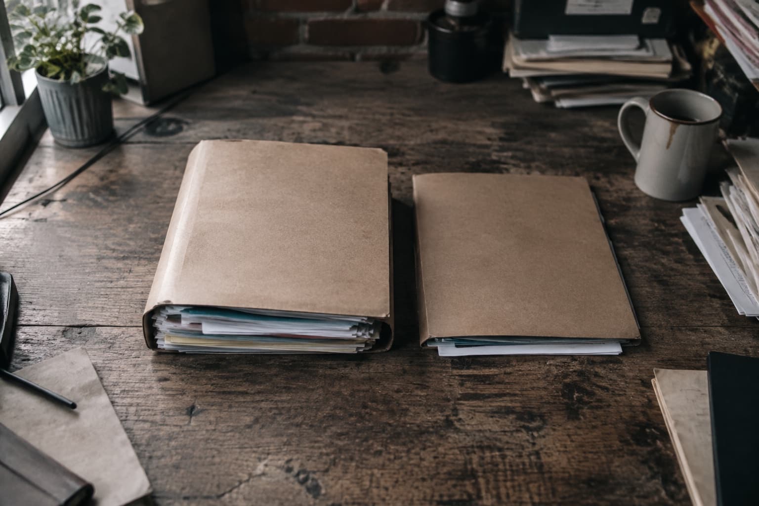 Two brown folders of different thicknesses on a desk